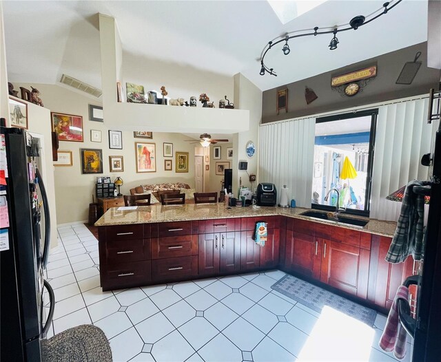 kitchen with black fridge, sink, vaulted ceiling, ceiling fan, and kitchen peninsula