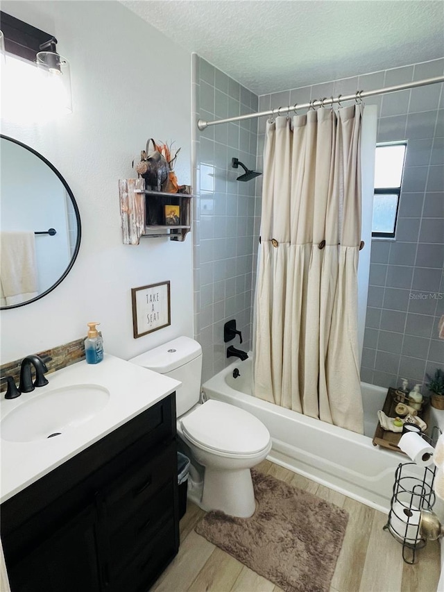 full bathroom featuring vanity, a textured ceiling, shower / bath combo with shower curtain, hardwood / wood-style flooring, and toilet