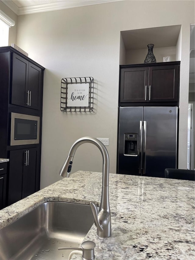 kitchen with built in microwave, stainless steel refrigerator with ice dispenser, sink, and light stone counters