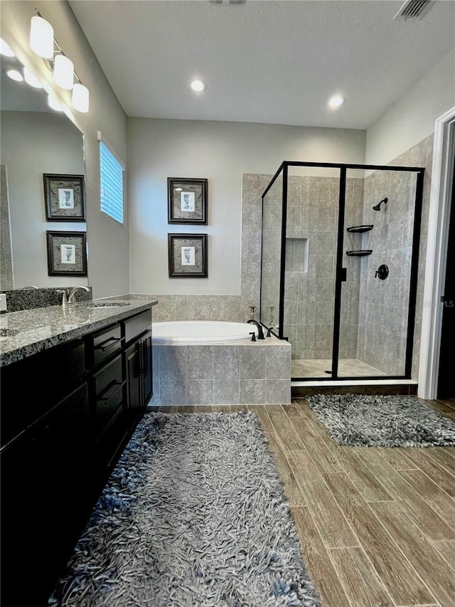 bathroom with vanity, shower with separate bathtub, and a textured ceiling