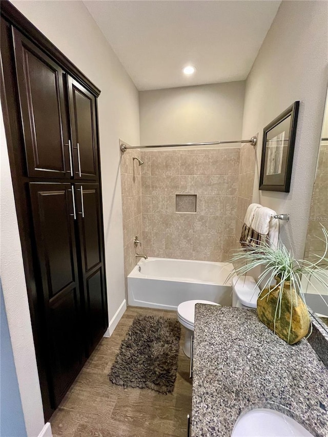 full bathroom featuring tiled shower / bath, wood-type flooring, toilet, and vanity