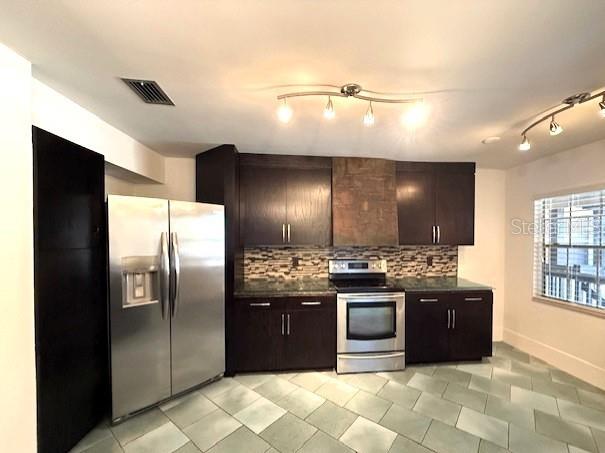 kitchen with dark brown cabinetry, decorative backsplash, stainless steel appliances, and light tile patterned flooring