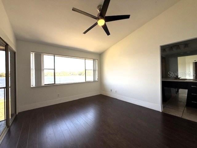 empty room featuring vaulted ceiling, dark hardwood / wood-style floors, and ceiling fan