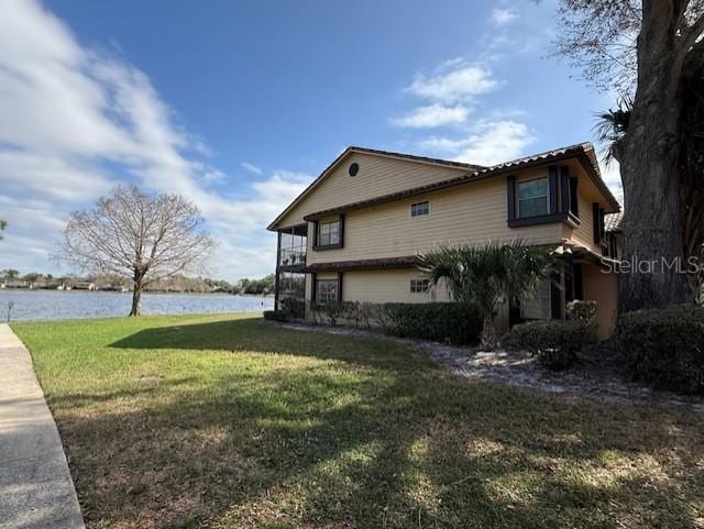 view of property exterior with a water view and a yard