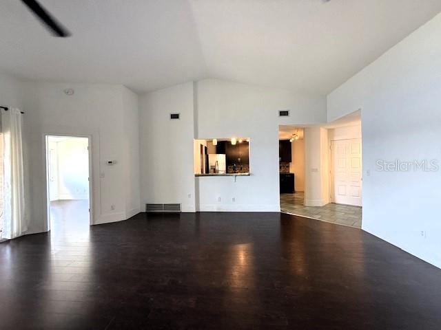 unfurnished living room with dark wood-type flooring and vaulted ceiling