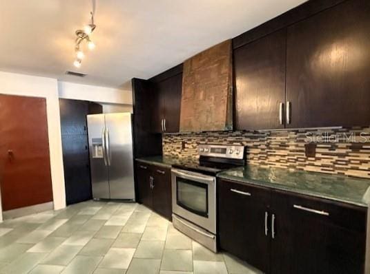 kitchen with tasteful backsplash, stainless steel appliances, wall chimney exhaust hood, and dark brown cabinets