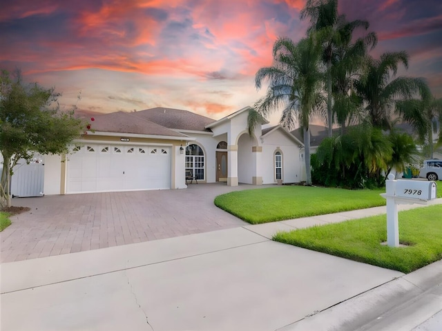 mediterranean / spanish-style house with a garage and a lawn