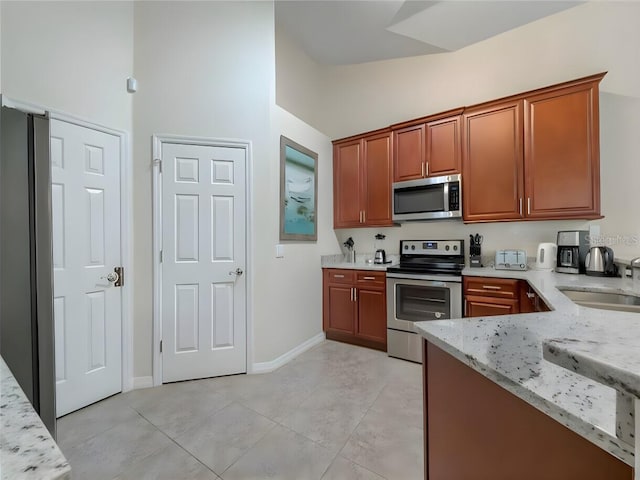 kitchen featuring light tile patterned floors, light stone counters, appliances with stainless steel finishes, sink, and high vaulted ceiling