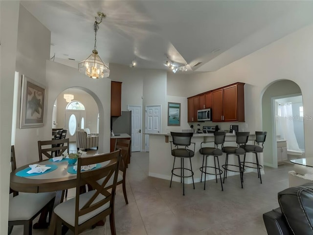 kitchen with plenty of natural light, a notable chandelier, light tile patterned floors, and kitchen peninsula