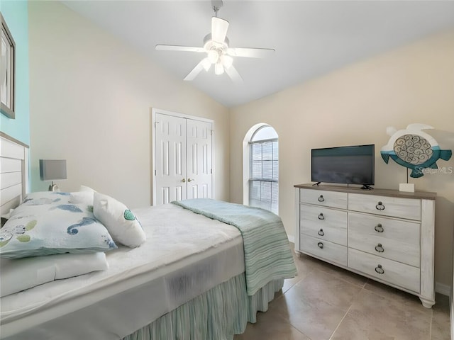 bedroom with vaulted ceiling, a closet, light tile patterned floors, and ceiling fan