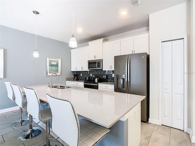 kitchen with appliances with stainless steel finishes, sink, hanging light fixtures, backsplash, and light tile patterned floors