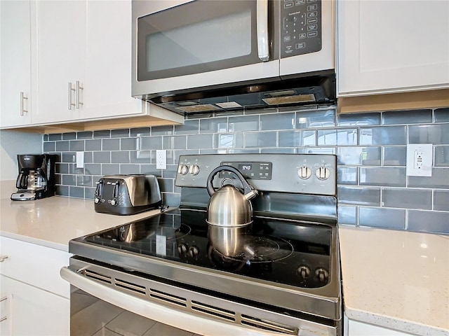 kitchen with appliances with stainless steel finishes, backsplash, and white cabinetry