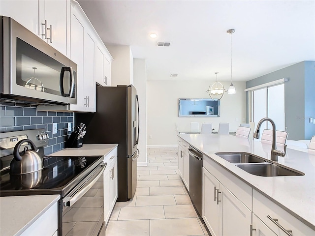 kitchen featuring light tile patterned flooring, white cabinetry, stainless steel appliances, pendant lighting, and sink