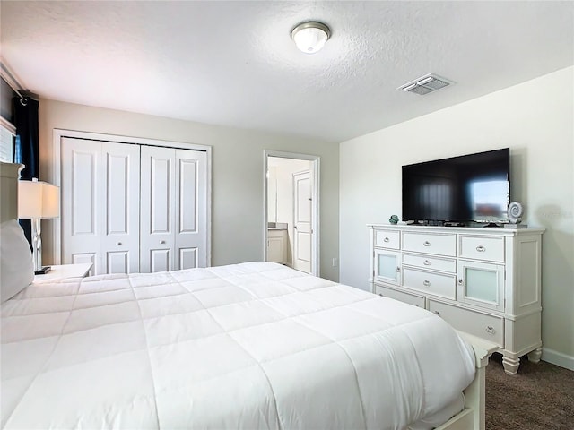 bedroom featuring ensuite bathroom, a textured ceiling, a closet, and carpet flooring