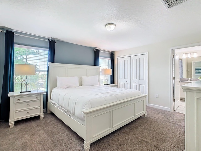 carpeted bedroom with ensuite bath and a closet