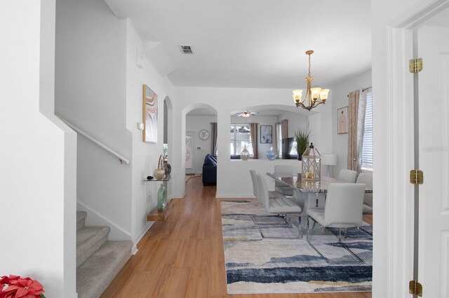 dining space with ceiling fan with notable chandelier and hardwood / wood-style floors