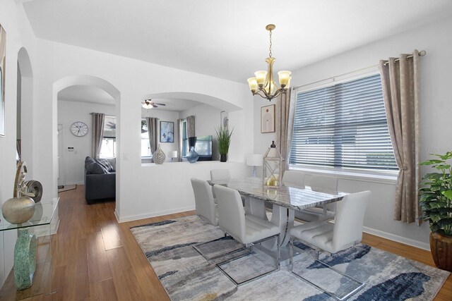 dining space featuring ceiling fan with notable chandelier and wood-type flooring