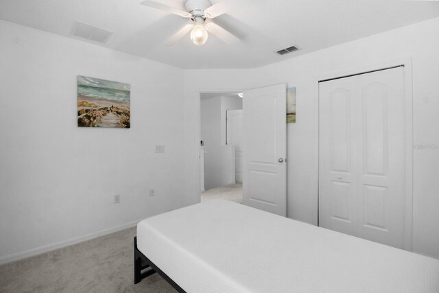 bedroom featuring light carpet, ceiling fan, and a closet