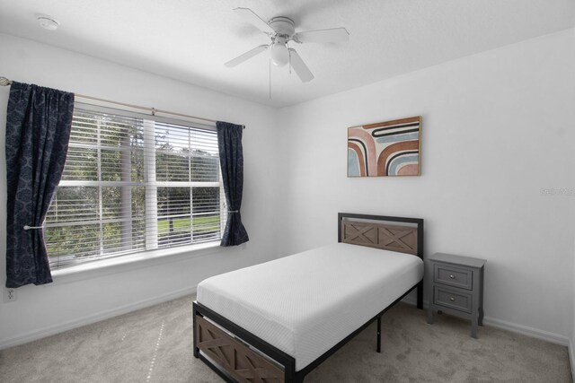 carpeted bedroom featuring ceiling fan and multiple windows