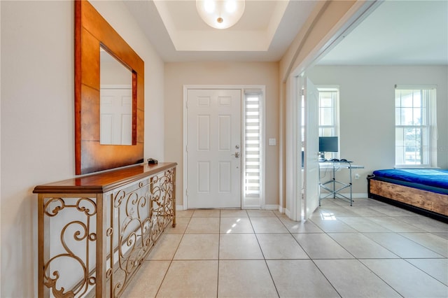 entrance foyer featuring a tray ceiling and light tile patterned floors