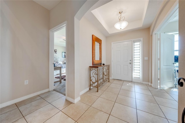 tiled foyer entrance featuring a raised ceiling and a wealth of natural light