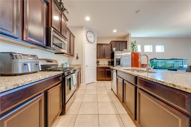 kitchen featuring appliances with stainless steel finishes, sink, light tile patterned floors, and dark brown cabinetry