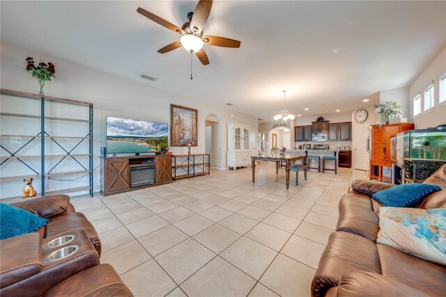 tiled living room with ceiling fan with notable chandelier