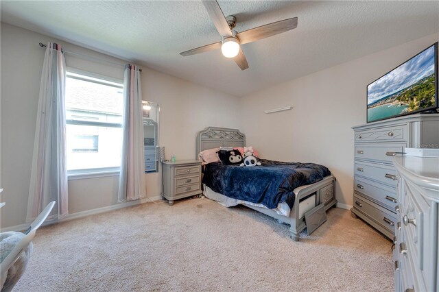 bedroom with multiple windows, light carpet, ceiling fan, and a textured ceiling