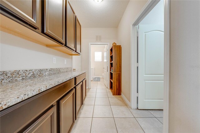 kitchen featuring light stone counters, light tile patterned floors, and a textured ceiling