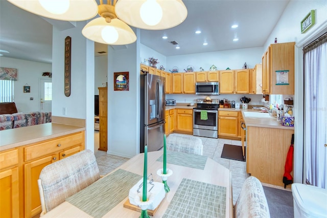 kitchen with light tile patterned flooring, appliances with stainless steel finishes, sink, and light brown cabinets