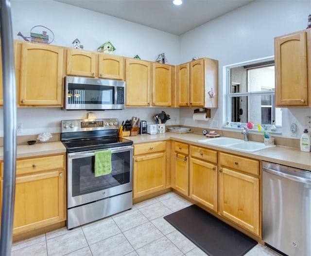 kitchen with sink, light brown cabinets, stainless steel appliances, and light tile patterned flooring