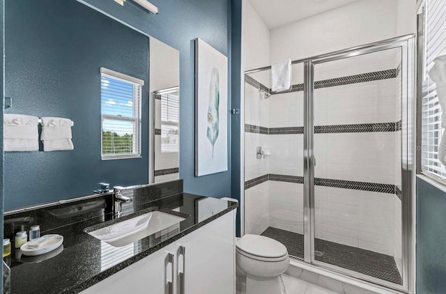 bathroom featuring toilet, a shower with shower door, and vanity