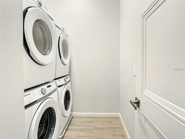 clothes washing area with light hardwood / wood-style floors and stacked washer and clothes dryer