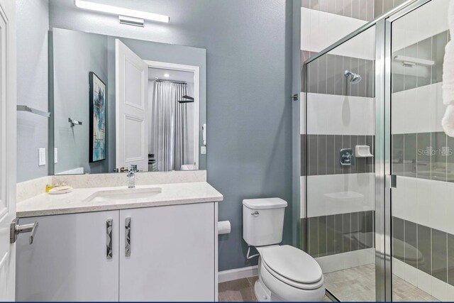 bathroom with toilet, a shower with shower door, tile patterned floors, and vanity