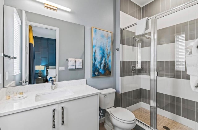 bathroom featuring vanity, toilet, and a shower with shower door