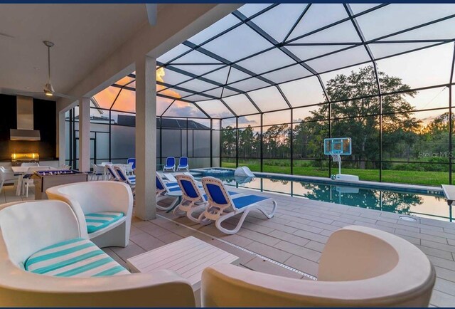 patio terrace at dusk with a lanai and a swimming pool with hot tub