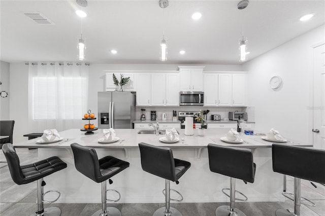 kitchen featuring stainless steel appliances, hanging light fixtures, sink, a kitchen bar, and light stone countertops