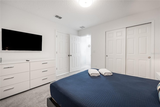 bedroom featuring a textured ceiling and light colored carpet