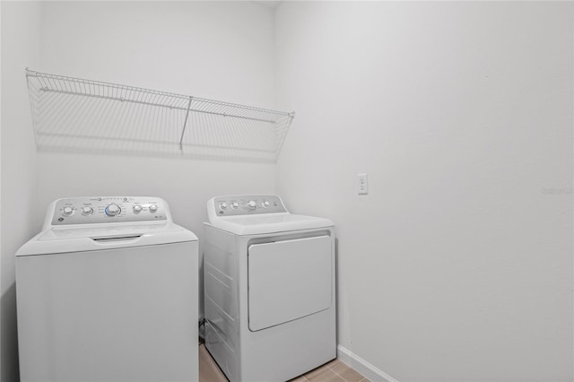 clothes washing area featuring light tile patterned floors and washer and clothes dryer