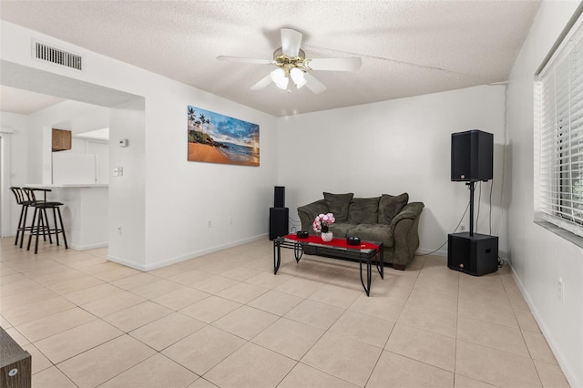 living room with a ceiling fan, light tile patterned flooring, a textured ceiling, and visible vents