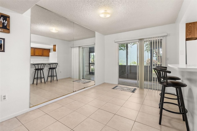 dining space with light tile patterned flooring, baseboards, and a textured ceiling