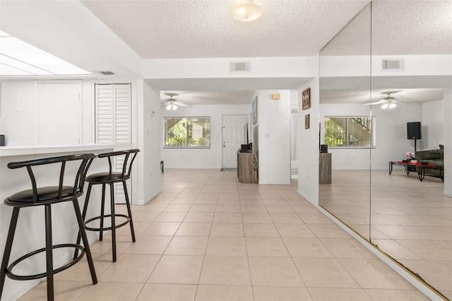 interior space with ceiling fan, visible vents, and light tile patterned floors