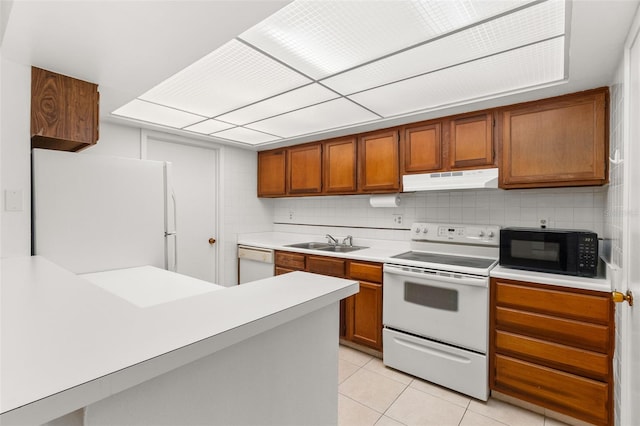 kitchen featuring light tile patterned flooring, light countertops, white appliances, under cabinet range hood, and a sink