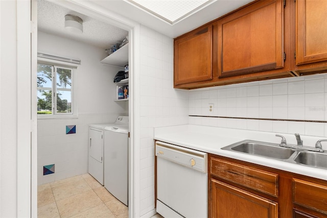 washroom featuring washer and clothes dryer, a sink, a textured ceiling, laundry area, and tile walls