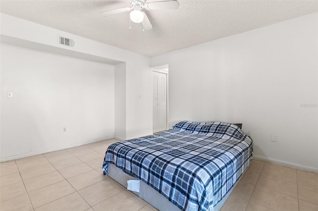 tiled bedroom featuring a ceiling fan, a textured ceiling, baseboards, and visible vents