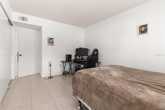 bedroom with light tile patterned flooring, a textured ceiling, and visible vents