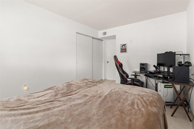 bedroom featuring visible vents, a closet, and a textured ceiling