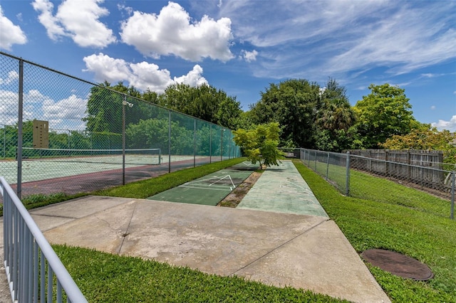 view of sport court featuring a lawn, fence, and shuffleboard