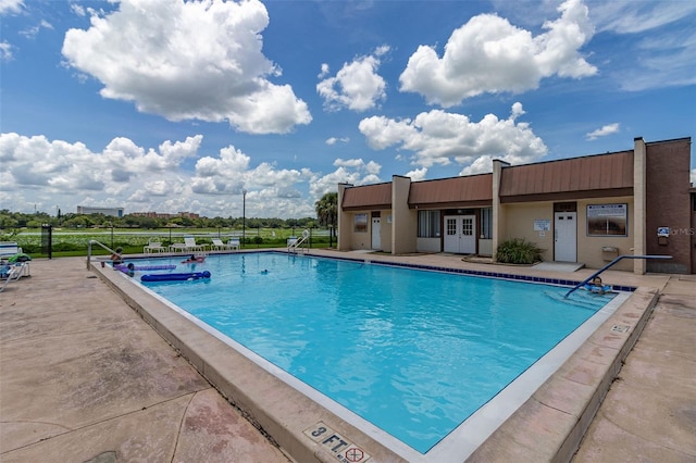 community pool with fence, french doors, and a patio area