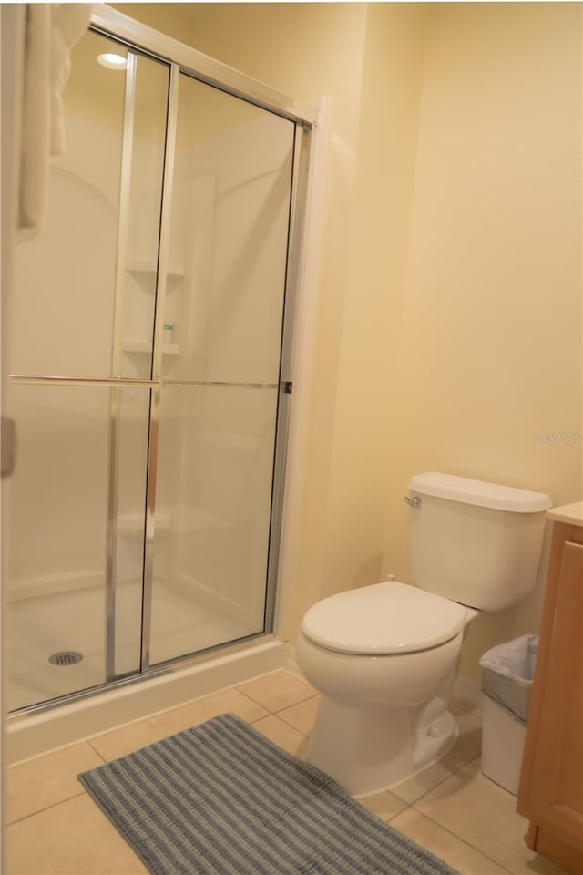 bathroom featuring tile patterned floors, vanity, an enclosed shower, and toilet